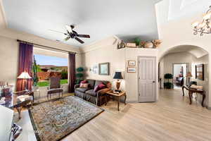 Living room featuring light wood-type flooring, ceiling fan, and arched walkways