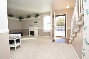 Doorway to outside featuring stairway, carpet floors, and a fireplace