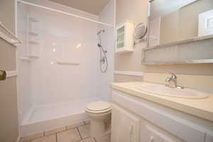 Bathroom with vanity, a shower, and light tile patterned flooring