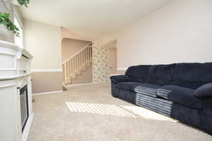Living room featuring light carpet, stairway, and a glass covered fireplace