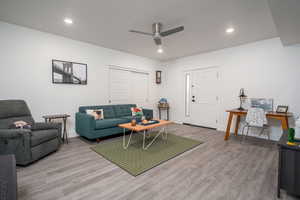 Basement living room with light wood-style floors, ceiling fan, and recessed lighting