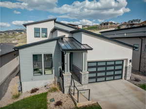 Modern home featuring a standing seam roof, stone siding, a metal roof, concrete driveway, and a garage