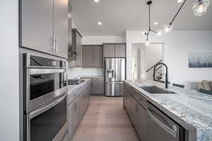 Kitchen featuring appliances with stainless steel finishes, decorative light fixtures, backsplash, light stone counters, and recessed lighting