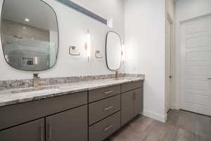 Primary bathroom with a shower stall, double vanity, and dark tile patterned floors