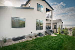 Back of property with stucco siding, a balcony, a patio area, and stairs