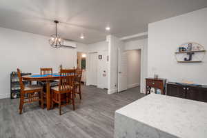 Basement dining area with light wood-style floors, recessed lighting, a chandelier, and a wall mounted air conditioner
