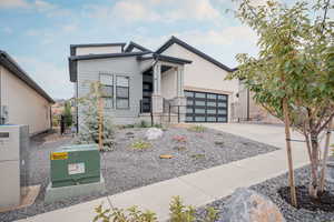 Modern home featuring driveway, stone siding, an attached garage, and stucco siding