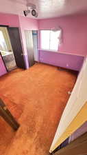 Unfurnished bedroom featuring carpet flooring, a textured ceiling, and a closet