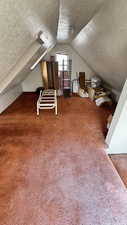 Bonus room with a textured ceiling, carpet, and lofted ceiling