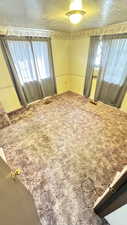 Carpeted empty room with a textured ceiling