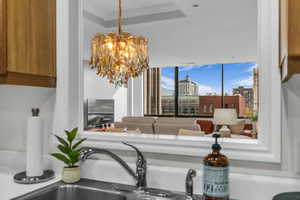 Kitchen view of crown molding, a chandelier, and brown cabinetry