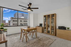 Office space featuring light colored carpet, a view of city, and a ceiling fan