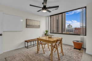 Carpeted office space with a view of city and ceiling fan