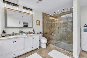 Bathroom featuring double vanity, a stall shower, and light tile patterned floors