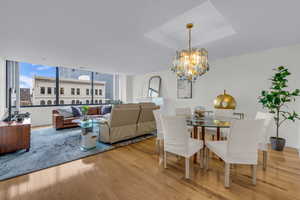 Dining room with light wood-style flooring, a tray ceiling, and a chandelier
