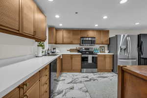Kitchen featuring black appliances, recessed lighting, light countertops, light marble finish floors, and brown cabinets