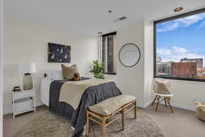 Bedroom featuring light carpet and a view of city