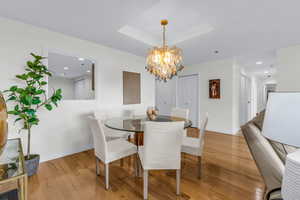 Dining space featuring light wood-style flooring, a raised ceiling, a chandelier, and recessed lighting