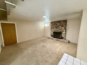 Unfurnished living room featuring a fireplace, carpet flooring, a textured ceiling, and wood walls