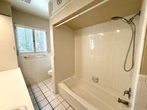 Bathroom featuring light tile patterned floors, shower / tub combination, and tile walls