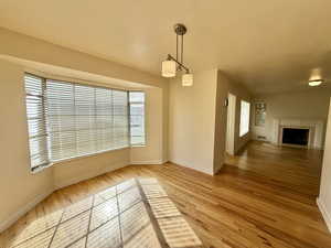 Unfurnished dining area featuring light wood-style flooring and a fireplace