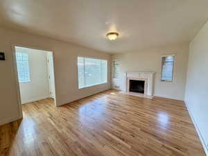 Unfurnished living room featuring a tile fireplace and light wood-style flooring