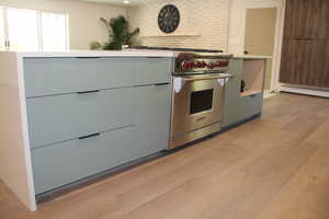 Kitchen with modern cabinets, light wood finished floors, premium range, light countertops, and gray cabinets