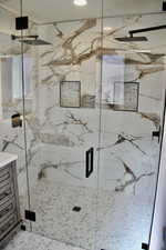Bathroom with a marble finish shower and recessed lighting