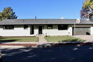 Ranch-style house featuring a front yard, roof with shingles, concrete driveway, and an attached garage