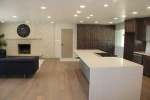 Kitchen with recessed lighting, light wood-style floors, a center island, modern cabinets, and light stone countertops