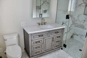 Full bathroom with vanity, a marble finish shower, and light tile patterned floors
