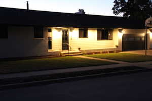 Ranch-style house featuring a front lawn, a chimney, driveway, and a garage