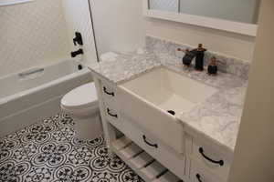 Bathroom with vanity, bathtub / shower combination, and light tile patterned floors