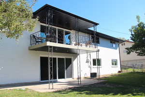 Rear view of property featuring a balcony, a patio, and brick siding