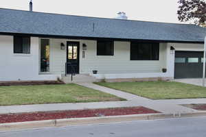 Ranch-style house with an attached garage, a shingled roof, and a front yard