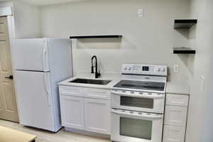 Kitchen featuring open shelves, white appliances, white cabinetry, light stone countertops, and light wood-type flooring