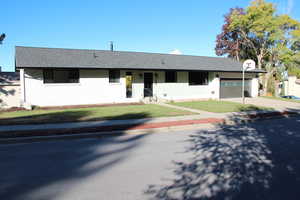Ranch-style home featuring driveway, a front yard, an attached garage, a shingled roof, and brick siding