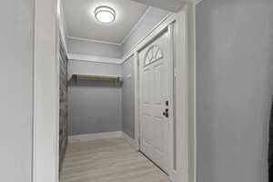 Entryway with wood finished floors and crown molding