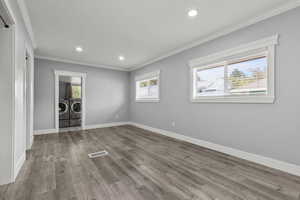 Unfurnished bedroom with ornamental molding, recessed lighting, wood finished floors, and washing machine and dryer