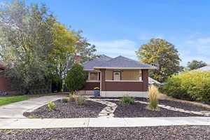View of front of property with a chimney, roof with shingles, a porch, and brick siding