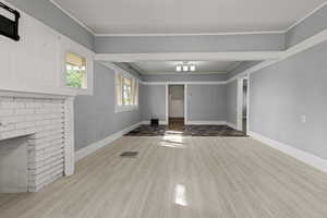 Unfurnished living room featuring light wood-type flooring, a fireplace, and ornamental molding