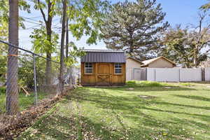 Fenced backyard featuring a storage shed