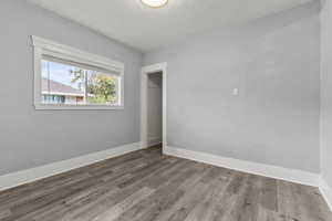 Unfurnished bedroom featuring wood finished floors, a closet, and a textured ceiling