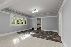 Spare room with dark wood-type flooring and crown molding