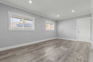 Empty room featuring ornamental molding, recessed lighting, and light wood-type flooring