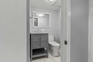 Half bathroom with light tile patterned floors and vanity