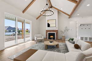 Living area with a fireplace, wood finished floors, beam ceiling, a chandelier, and high vaulted ceiling