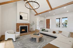 Living room featuring beam ceiling, wood finished floors, a brick fireplace, high vaulted ceiling, and a chandelier