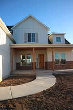 View of front of property with board and batten siding, covered porch, and brick siding