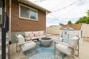 Fenced backyard with an outdoor living space with a fire pit, a patio, and an outdoor structure